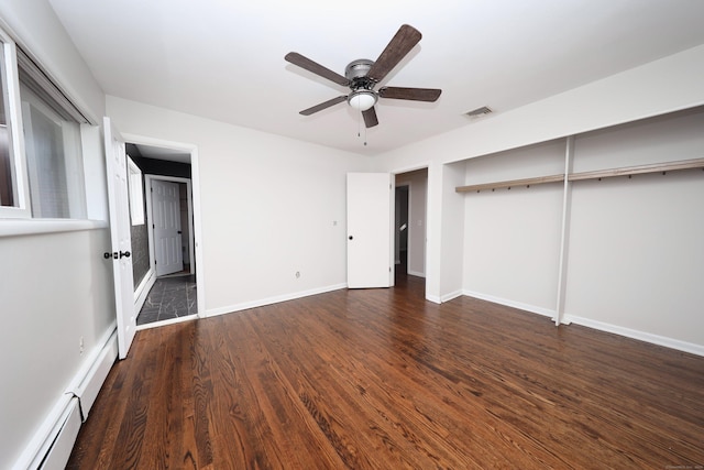 unfurnished bedroom with ceiling fan, baseboard heating, dark wood-type flooring, and a closet