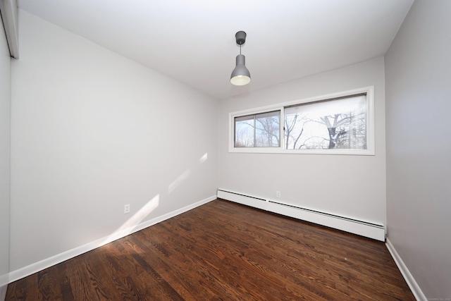 spare room featuring dark hardwood / wood-style flooring and a baseboard heating unit