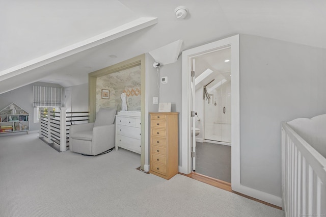 carpeted bedroom featuring ensuite bath and vaulted ceiling