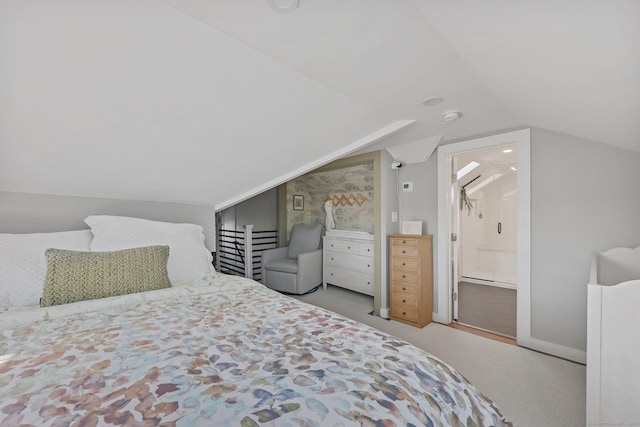 bedroom with light carpet, lofted ceiling, and ensuite bathroom