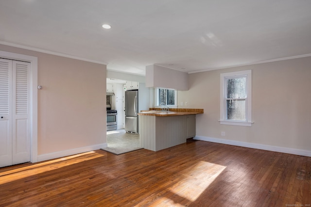 kitchen featuring kitchen peninsula, stainless steel appliances, plenty of natural light, and hardwood / wood-style flooring