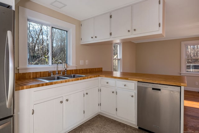 kitchen featuring kitchen peninsula, appliances with stainless steel finishes, white cabinetry, and plenty of natural light