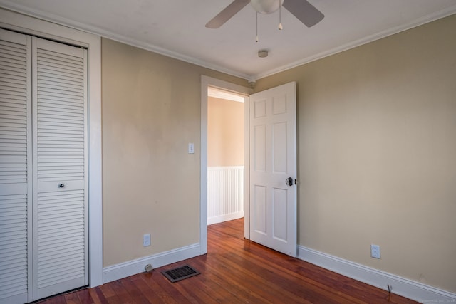 unfurnished bedroom featuring ceiling fan, a closet, dark wood-type flooring, and ornamental molding