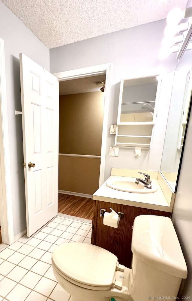 bathroom with tile patterned floors, vanity, a textured ceiling, and toilet