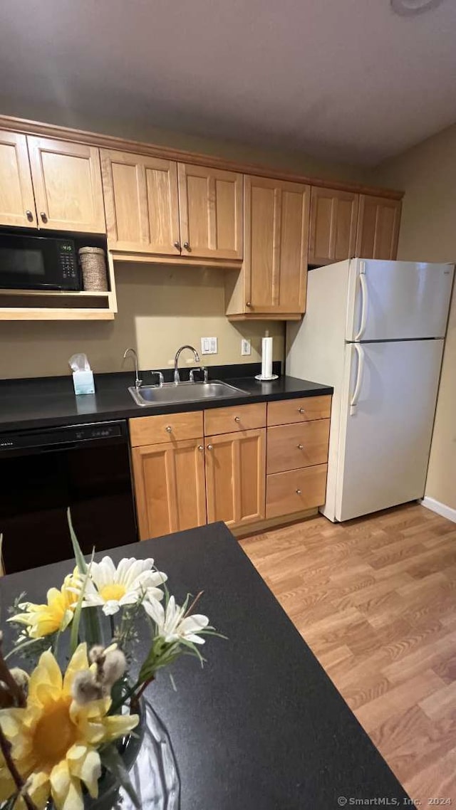 kitchen with sink, black appliances, and light hardwood / wood-style floors