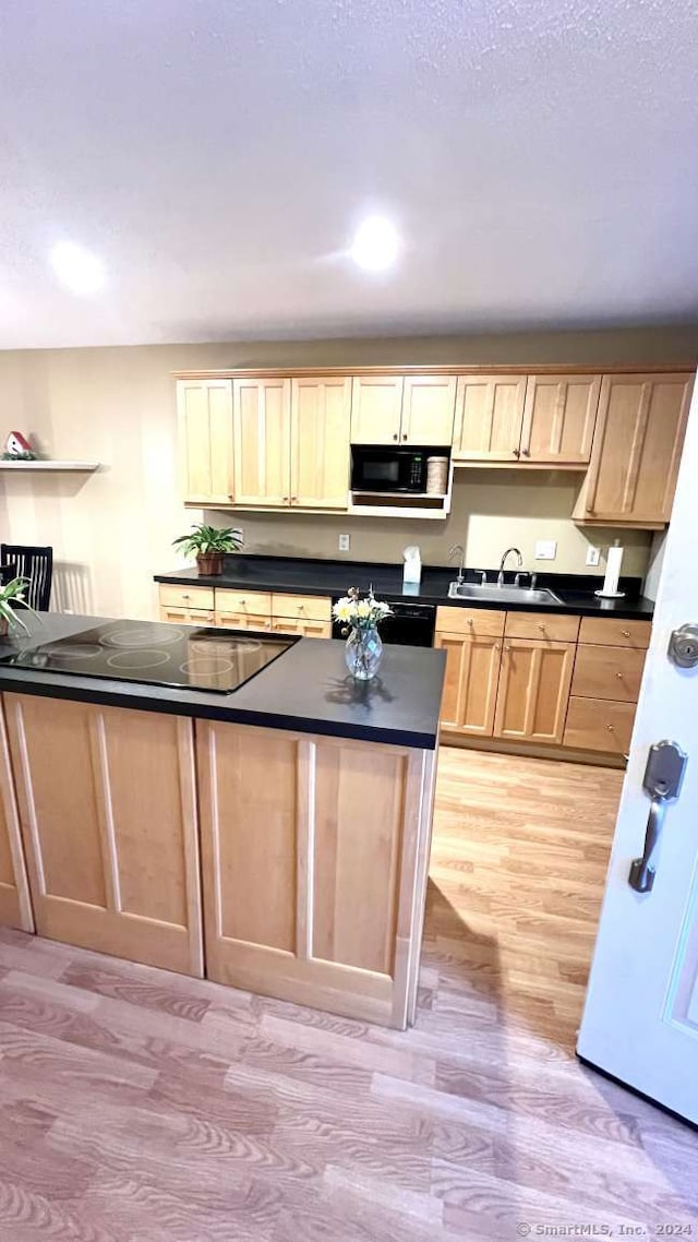 kitchen with light brown cabinetry, sink, light hardwood / wood-style floors, and black appliances