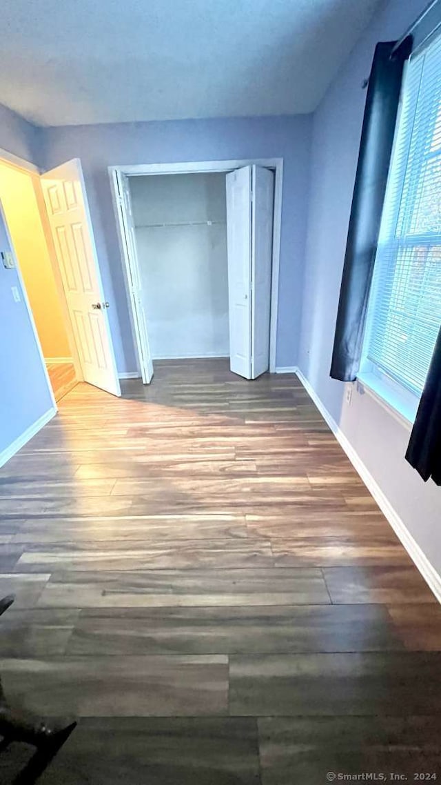 unfurnished bedroom featuring dark hardwood / wood-style flooring and a closet