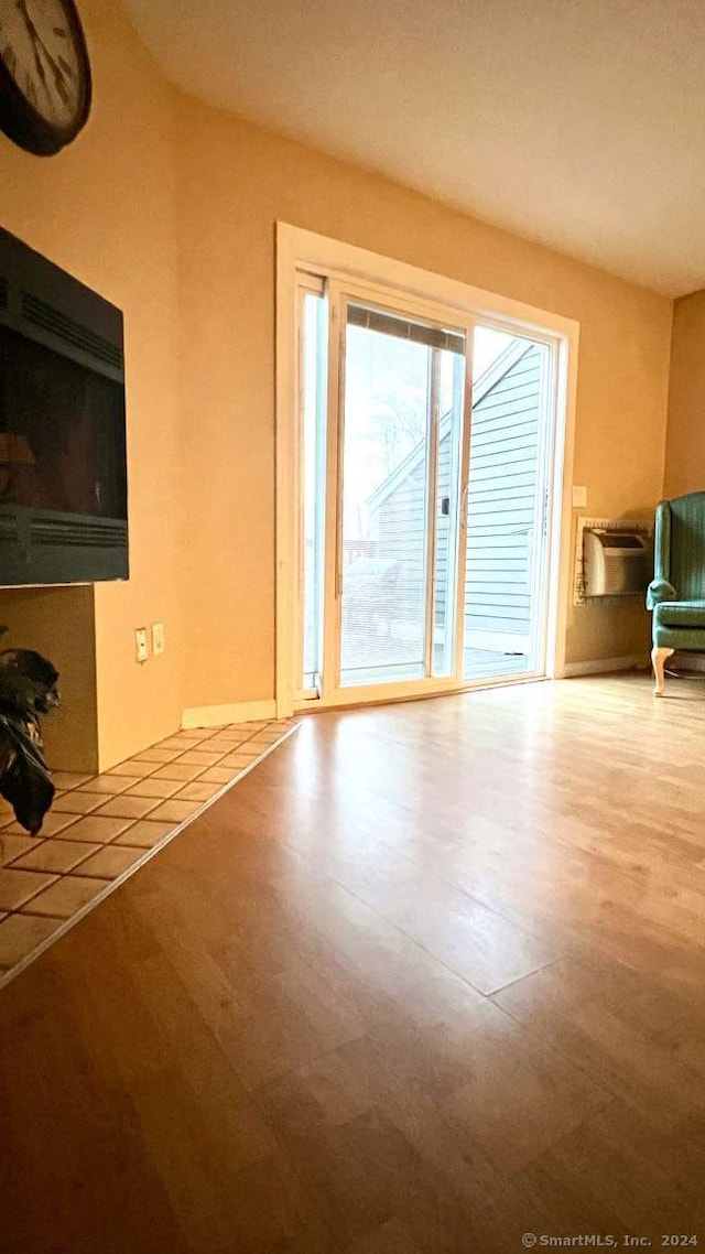 unfurnished living room featuring wood-type flooring and a wall mounted AC