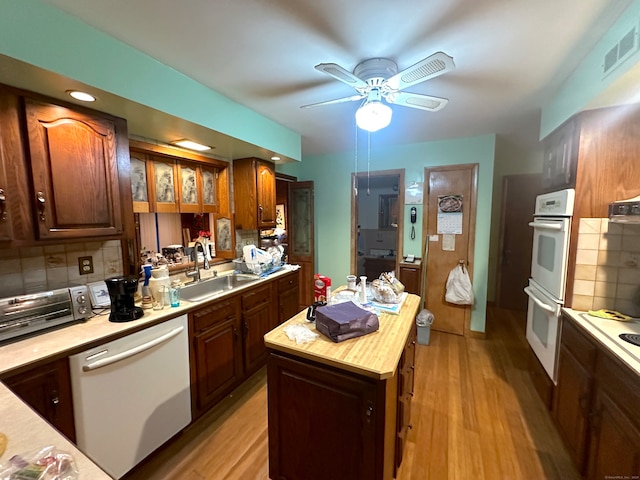 kitchen with a center island, white appliances, sink, and light hardwood / wood-style flooring