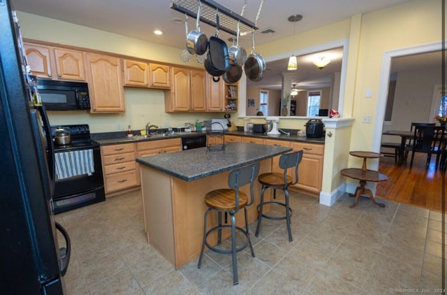 kitchen with a breakfast bar area, a peninsula, a center island, black appliances, and dark countertops