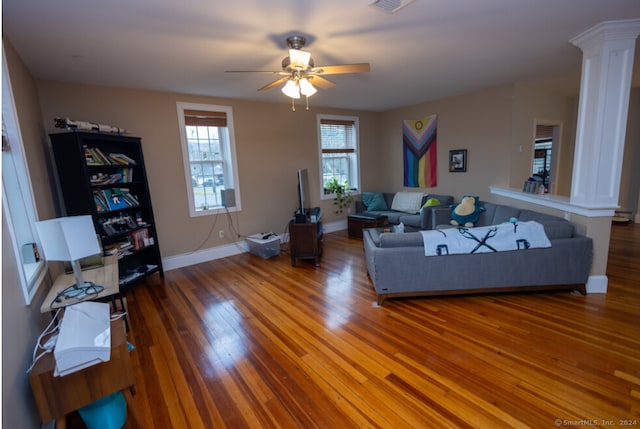 living room featuring wood-type flooring, ornate columns, and ceiling fan