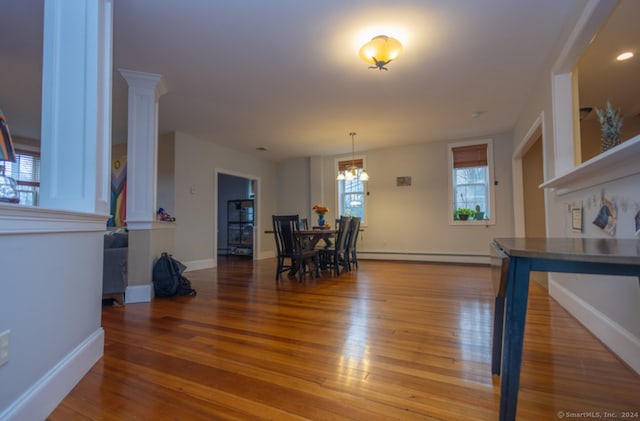 dining space featuring baseboard heating, a chandelier, and wood-type flooring