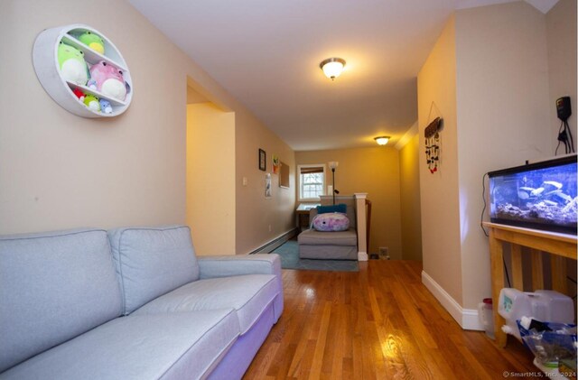 living room with a baseboard heating unit, wood finished floors, and baseboards