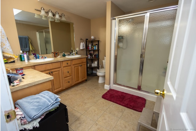 bathroom with toilet, vanity, tile patterned floors, and an enclosed shower