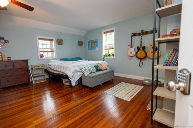 bedroom with ceiling fan, dark wood-type flooring, and vaulted ceiling