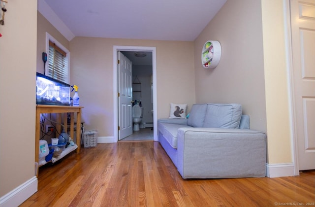 sitting room with baseboard heating, wood finished floors, and baseboards