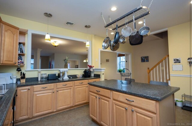 kitchen with a center island, light brown cabinetry, decorative light fixtures, light tile patterned flooring, and kitchen peninsula