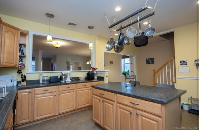 kitchen with visible vents, dark countertops, a center island, light brown cabinets, and pendant lighting