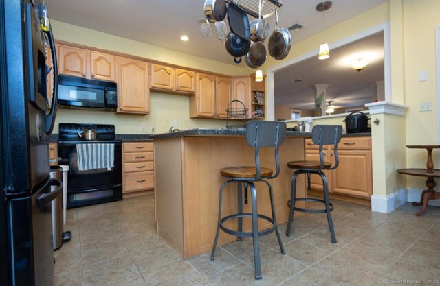 kitchen with hanging light fixtures, kitchen peninsula, a kitchen bar, light tile patterned floors, and black appliances