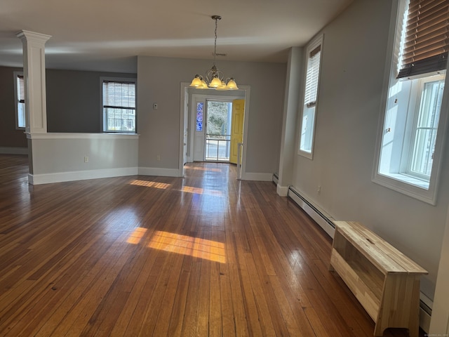 interior space with baseboards, dark wood finished floors, a baseboard radiator, an inviting chandelier, and ornate columns