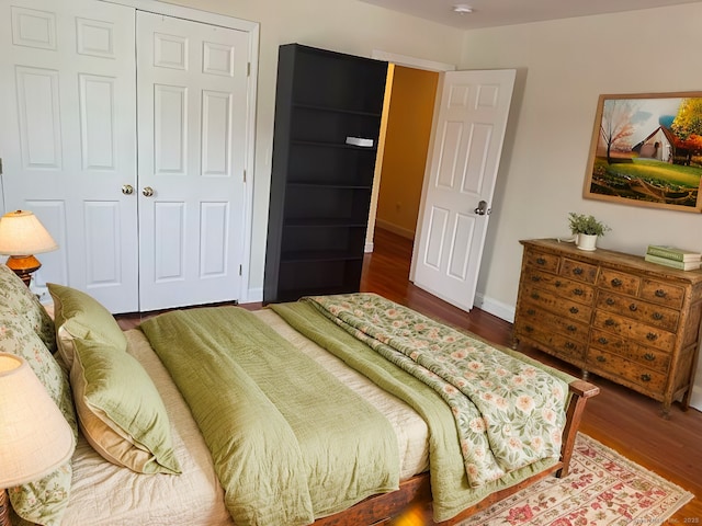 bedroom with a closet, dark wood finished floors, and baseboards