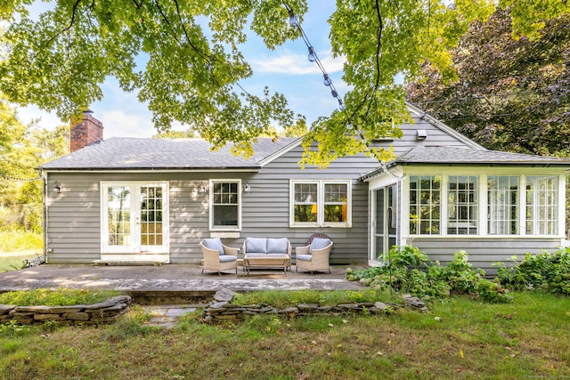 rear view of house featuring outdoor lounge area, a patio area, roof with shingles, and a chimney