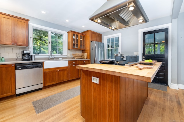 kitchen featuring a kitchen island, island range hood, wood counters, sink, and stainless steel appliances