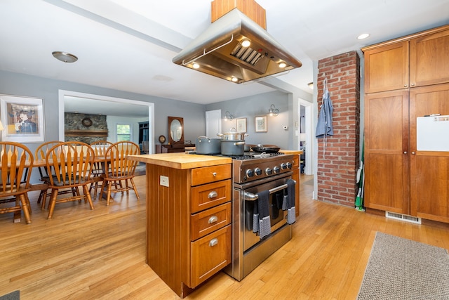 kitchen with high end stainless steel range oven, island range hood, butcher block countertops, and light hardwood / wood-style flooring