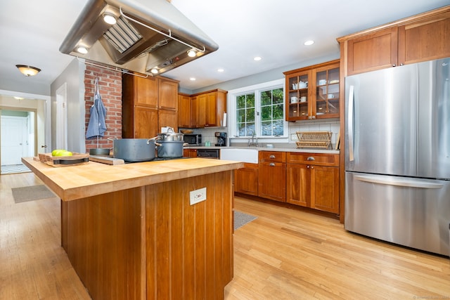 kitchen featuring stainless steel fridge, ventilation hood, a kitchen island, wood counters, and decorative backsplash