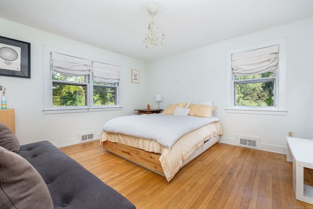 bedroom featuring wood-type flooring and an inviting chandelier