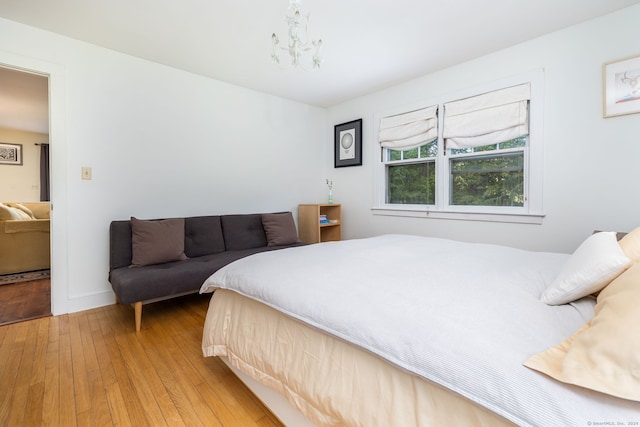 bedroom featuring light wood-type flooring, baseboards, and a notable chandelier