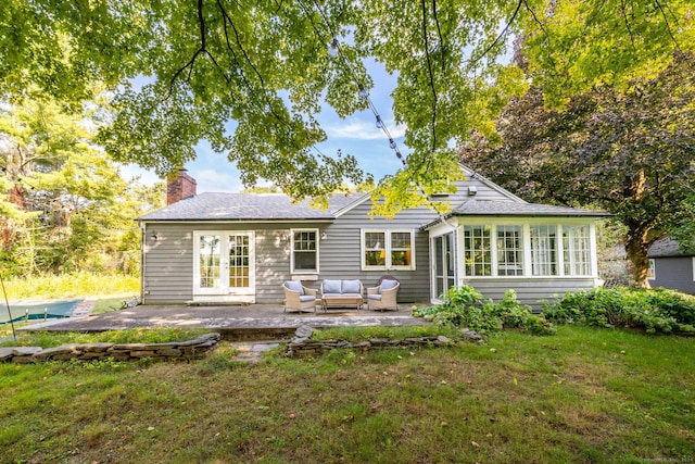 rear view of house with a chimney, outdoor lounge area, a patio area, and a yard