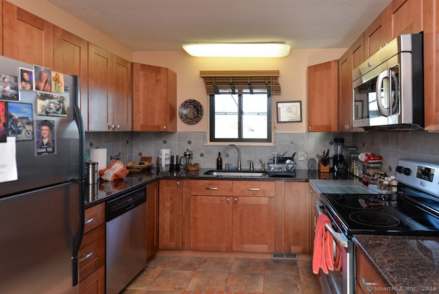 kitchen featuring appliances with stainless steel finishes, a textured ceiling, tasteful backsplash, and sink