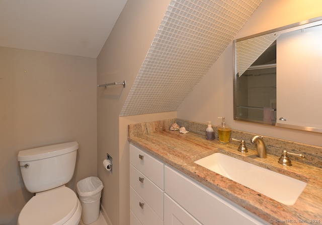 bathroom with toilet, vanity, and vaulted ceiling