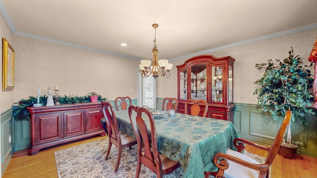 dining area featuring a notable chandelier, light wood-type flooring, and ornamental molding