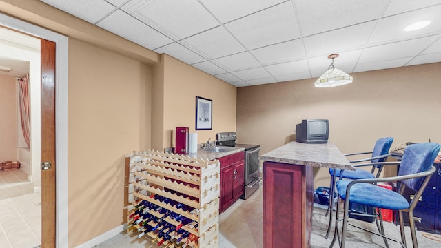 tiled office space with a paneled ceiling and sink