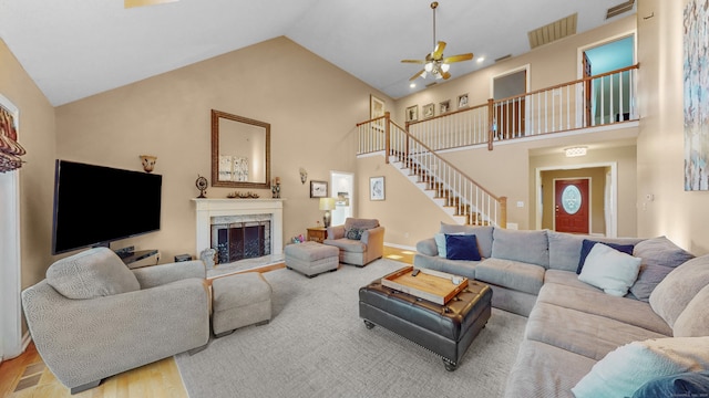 living room with light hardwood / wood-style floors, high vaulted ceiling, ceiling fan, and a premium fireplace