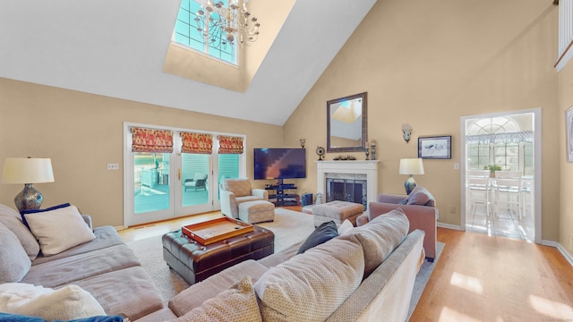 living room with an inviting chandelier, light hardwood / wood-style floors, and high vaulted ceiling