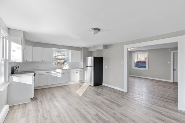 kitchen featuring white cabinets, light wood-type flooring, backsplash, and stainless steel refrigerator