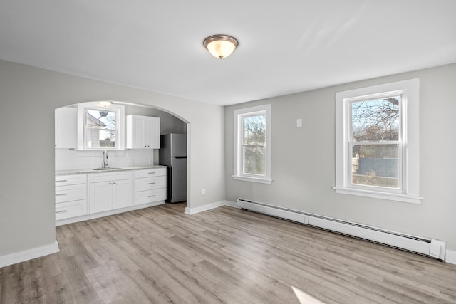 interior space with baseboard heating, plenty of natural light, and light wood-type flooring