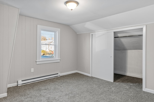 unfurnished bedroom featuring a closet, carpet floors, lofted ceiling, and a baseboard heating unit