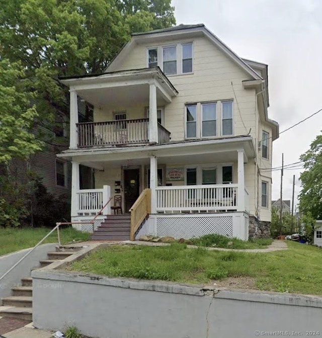 view of front of house with a porch, a balcony, and a front lawn