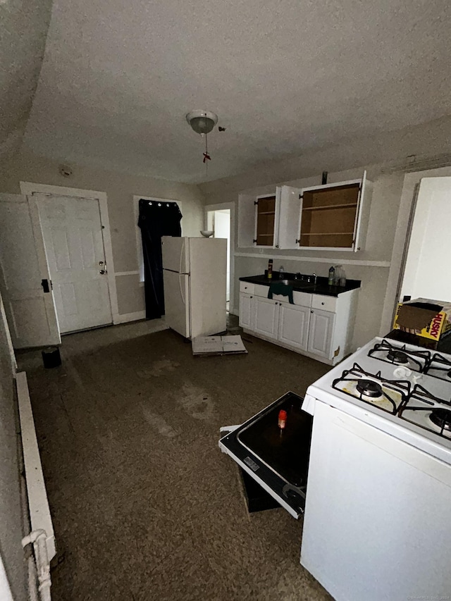 kitchen with white cabinets, dark carpet, white appliances, and a textured ceiling