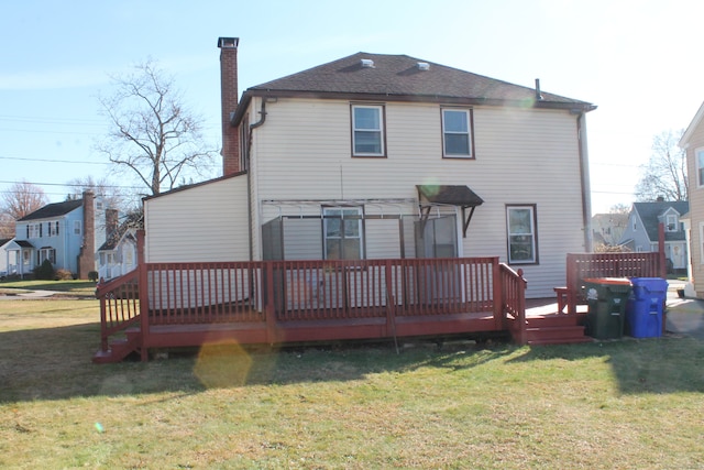 rear view of house featuring a wooden deck and a yard