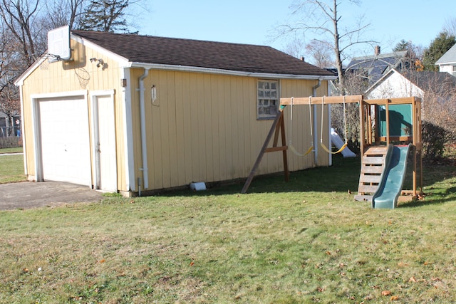 view of outdoor structure with a garage, a playground, and a yard