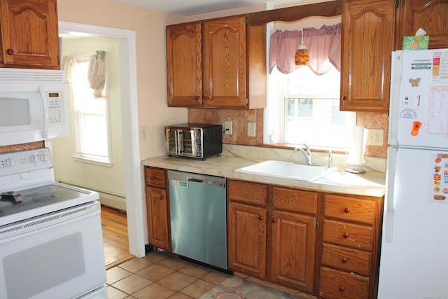 kitchen with light tile patterned floors, white appliances, sink, and a wealth of natural light