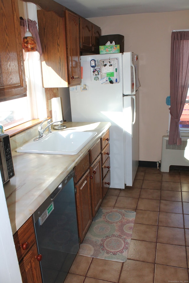 kitchen with radiator, sink, black dishwasher, white refrigerator, and light tile patterned flooring