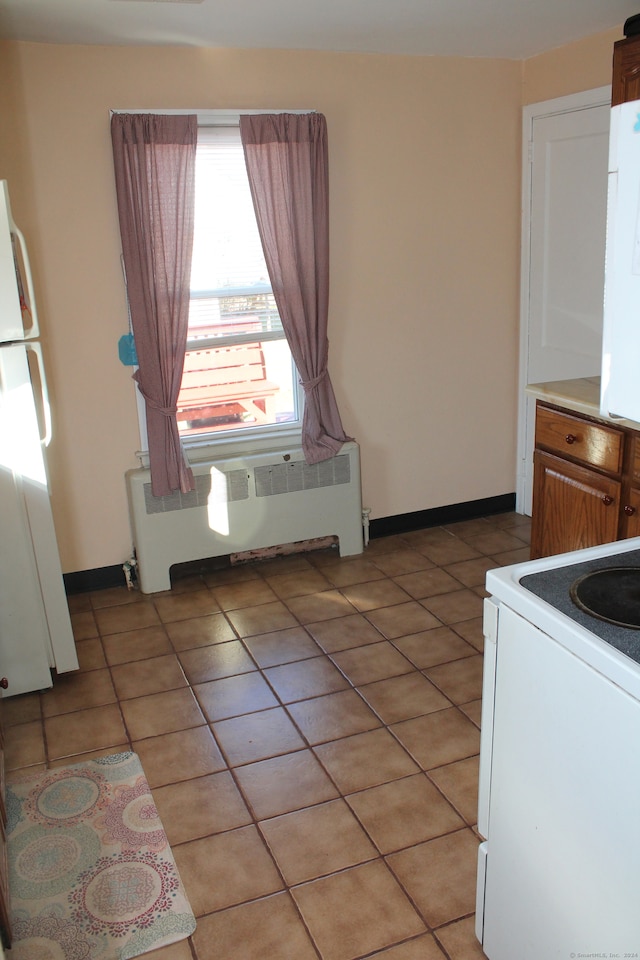 kitchen with white electric range oven, radiator heating unit, and light tile patterned floors