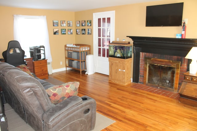 living room featuring hardwood / wood-style flooring and a brick fireplace