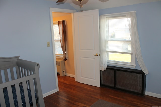 bedroom featuring ceiling fan, dark hardwood / wood-style flooring, radiator, and multiple windows